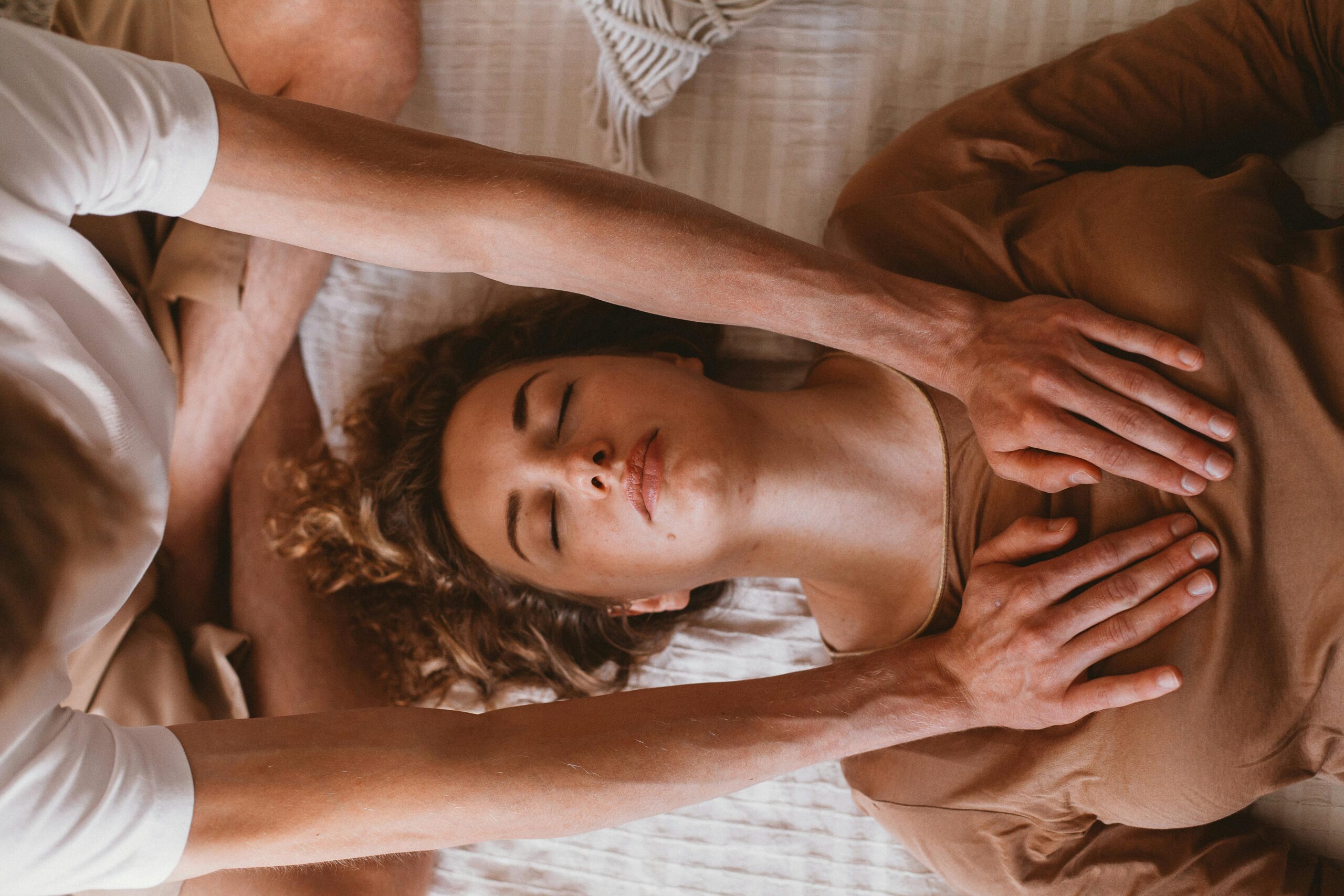 Craniosacral therapist gently placing hands on a woman's head during a somatic healing session